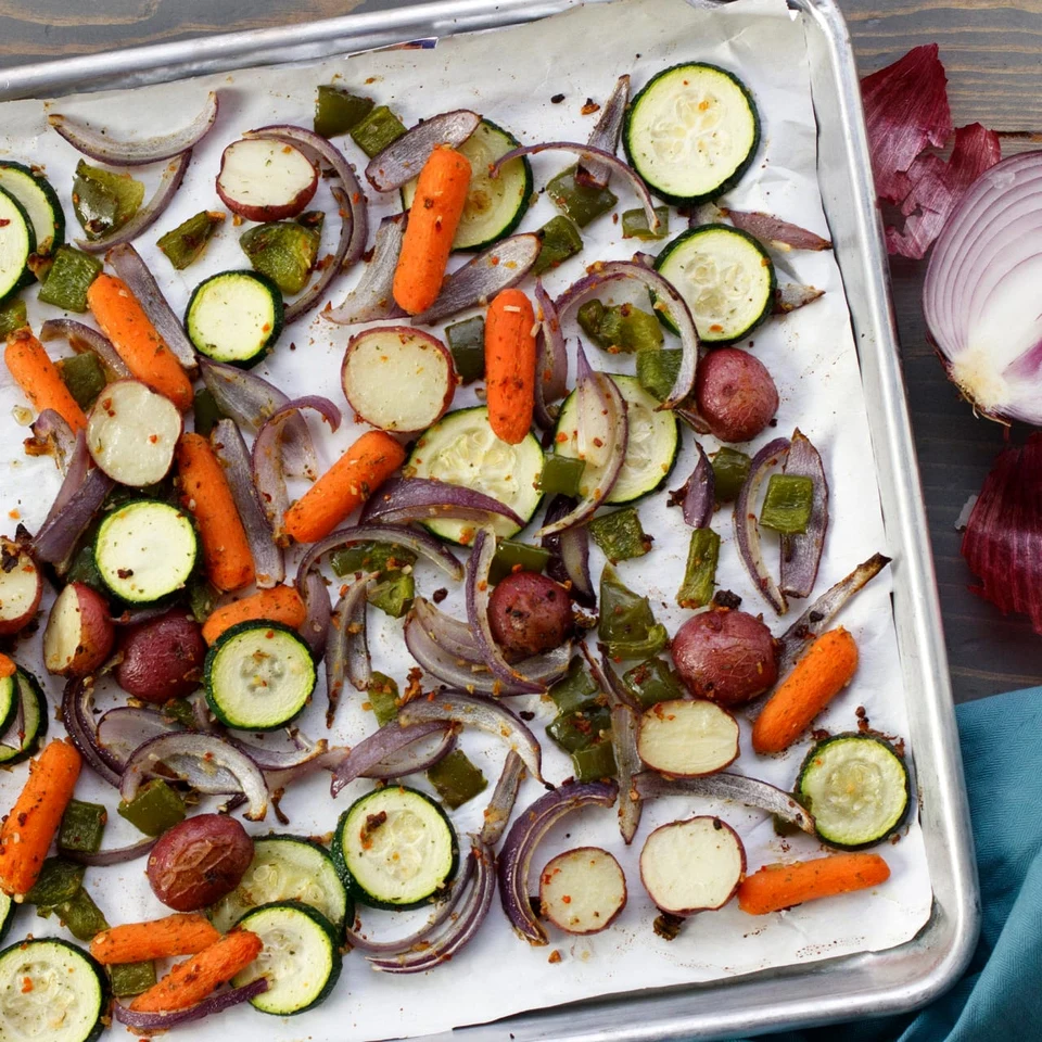 Roasted carrots, zucchini and onions on a baking tray